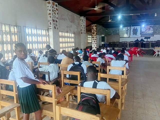 Students seated at wooden desks in a hall